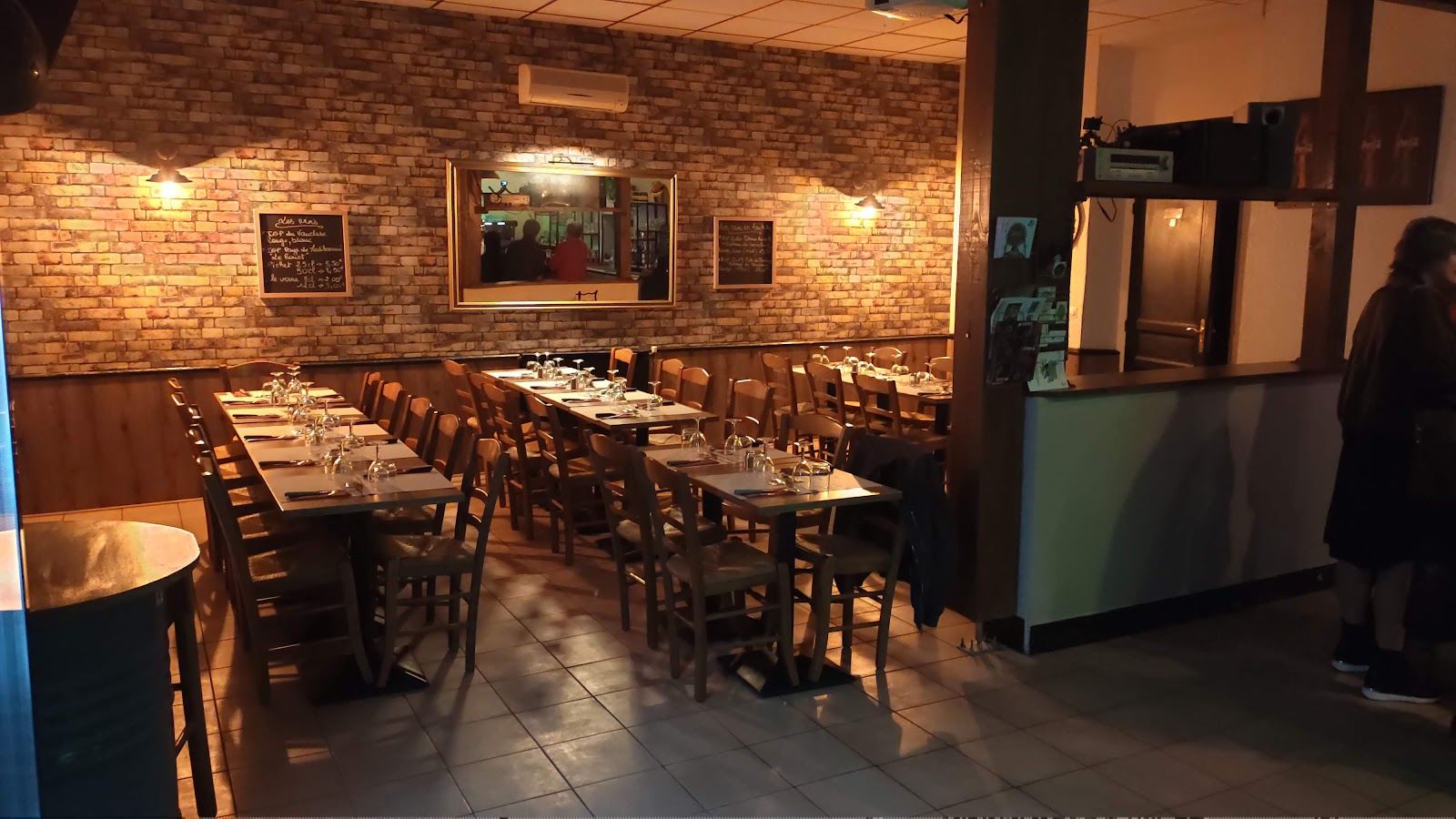 La salle en lumière chaude, longues tables dressées