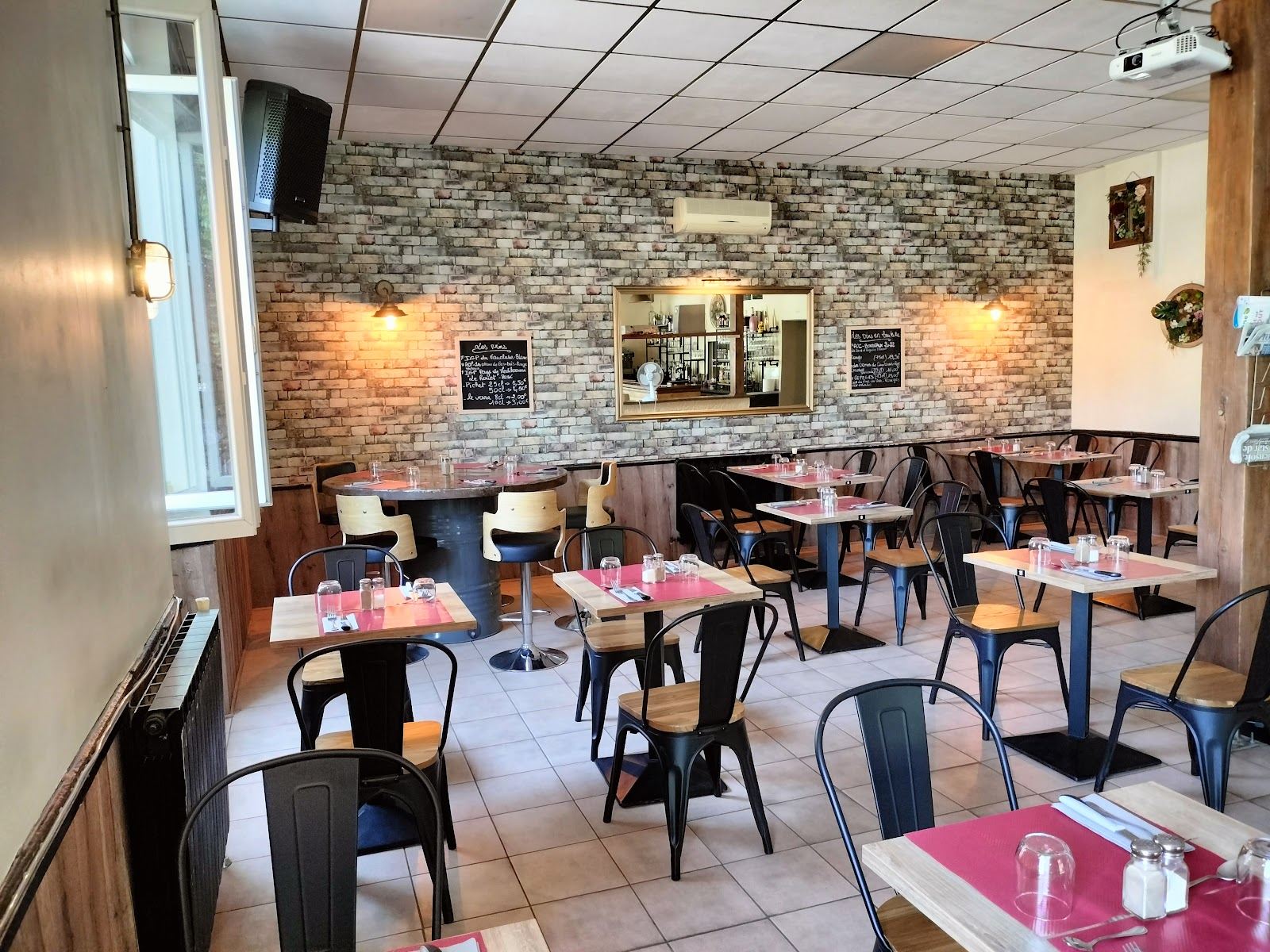La salle du restaurant, mur en pierre et tables dressées